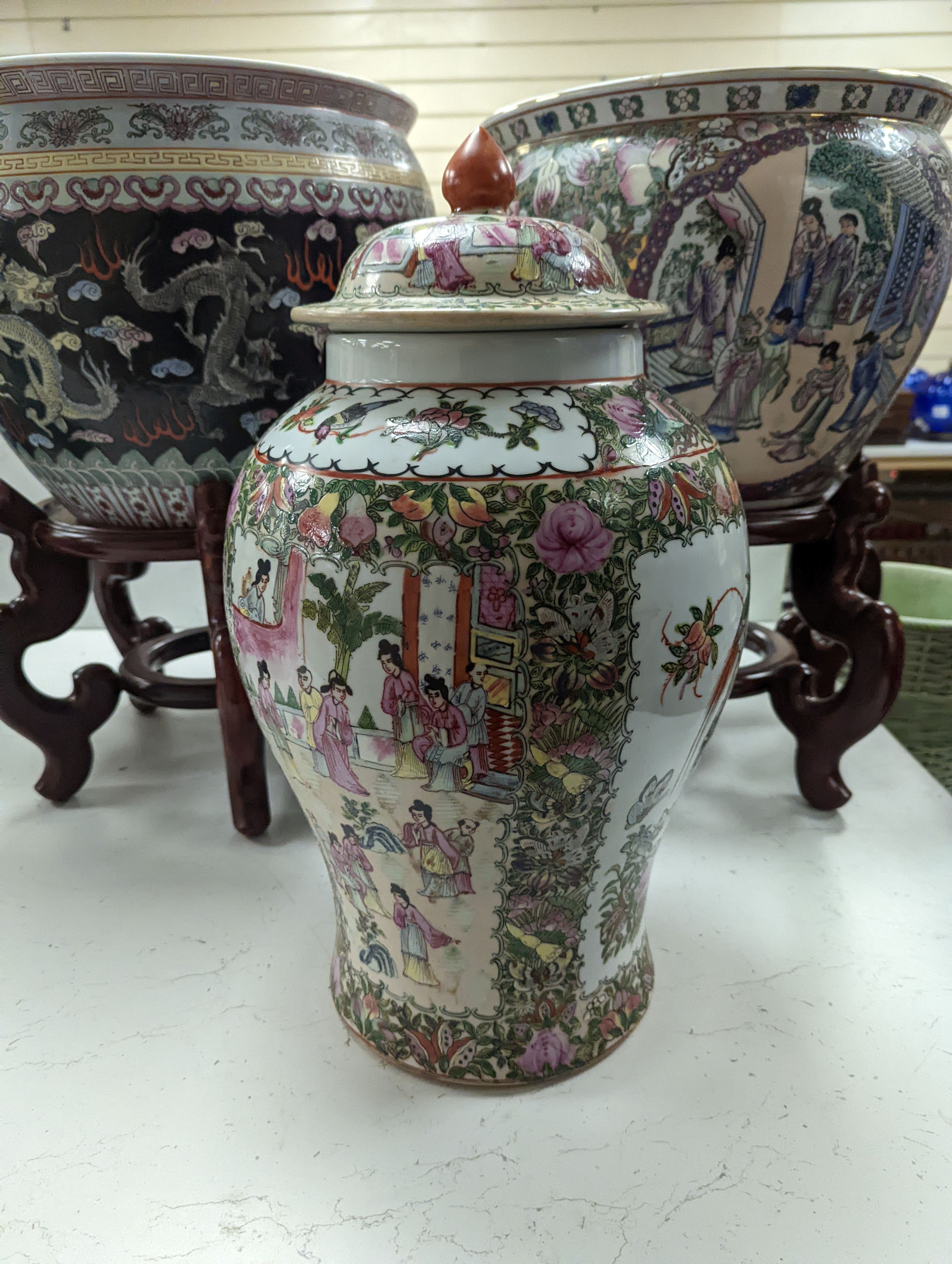 A pair of Chinese fish bowls on hardwood stands and a similar jar and cover, Fish bowls and stands 54 cms high.